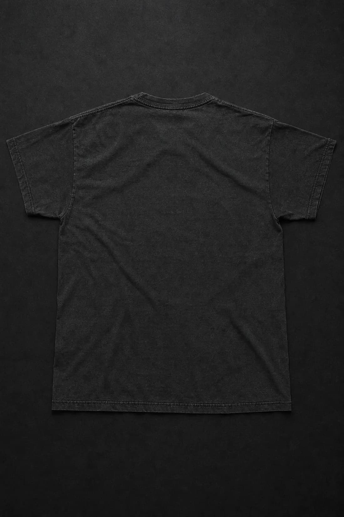 Washed black tee laid flat, back facing up, the Statement screen printed across the shoulders in off-white ink.